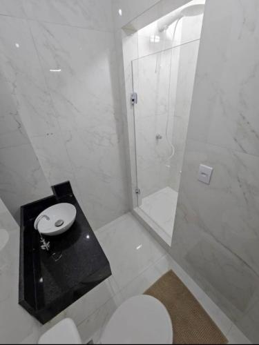a white bathroom with a shower and a toilet at Apartamento Central in Cascavel