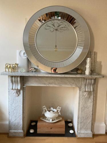 a mirror on top of a stone fireplace with a mirror at Luxurious tranquil large bedroom and bathroom suite with rooftop views in interior designed Georgian Townhouse in London