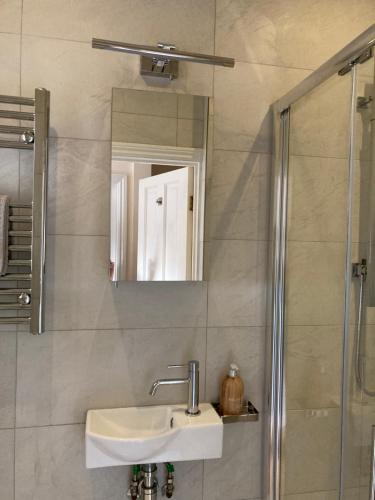 a bathroom with a sink and a shower with a mirror at Luxurious tranquil large bedroom and bathroom suite with rooftop views in interior designed Georgian Townhouse in London