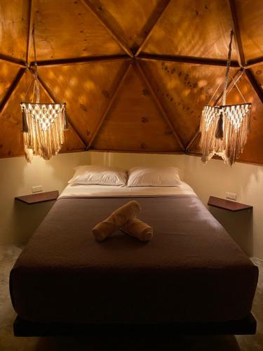 a teddy bear laying on a bed in a room at Frequency Beachfront Domes El Cuyo in El Cuyo