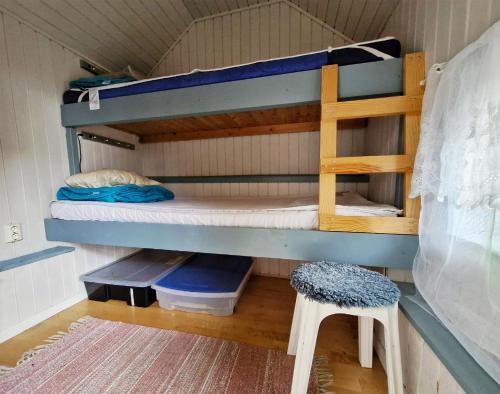 a bunk bed room with two bunk beds and a stool at Unikt sommarboende in Färjestaden