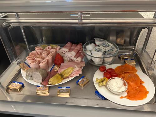 a refrigerator with two plates of food and other foods at Hotel Villa-Bassermann, stilvoll, 2 Min zum Schloss, schnelles WLAN & Parkplatz in Schwetzingen