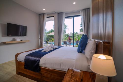 een slaapkamer met een groot bed en een televisie bij Sinapa Suites in Ko Pha Ngan
