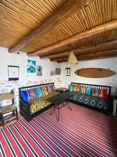 a living room with a couch and a surfboard on the wall at Studio Surf House Kaouki in Sidi Kaouki