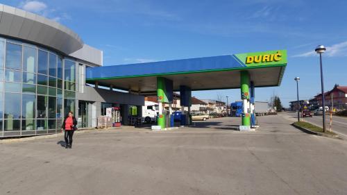 a woman walking past a chunk gas station at Durić doo in Cazin