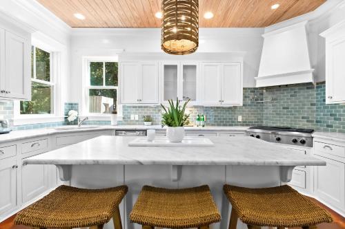 a kitchen with white cabinets and a large island with chairs at Seagrove Sun in Santa Rosa Beach
