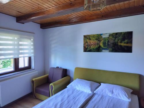 a bedroom with a bed and a chair and a painting at Casa Opal in Săcele