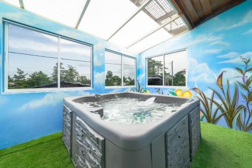 een jacuzzi in een blauwe kamer met ramen bij The Dorset on Ashby in Chaguanas Village