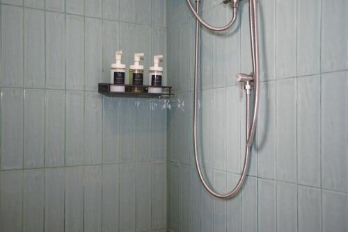 een badkamer met een douche en drie flessen op een plank bij Sinapa Suites in Ko Pha Ngan