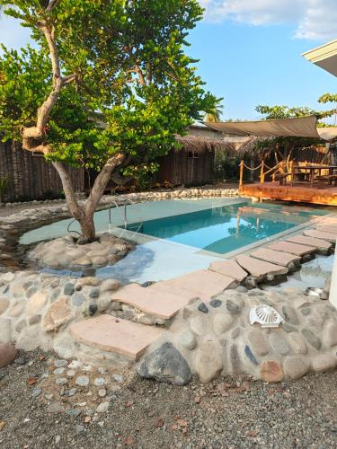 a swimming pool with a tree and rocks around it at Hostel Flakos in Zihuatanejo