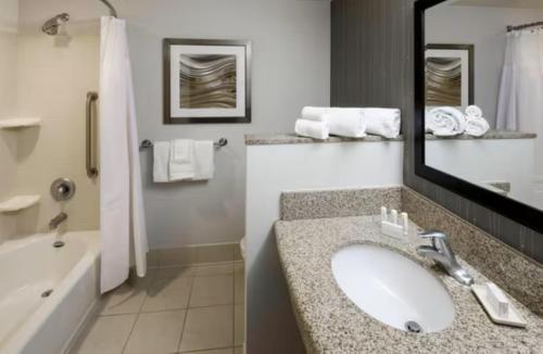 a bathroom with a sink and a tub and a mirror at Courtyard Harrisonburg in Harrisonburg