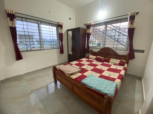 ein Schlafzimmer mit einem Bett in einem Zimmer mit zwei Fenstern in der Unterkunft Jk homestay Mysore in Mysore