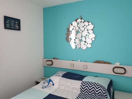 una camera da letto con una parete blu, un letto e un lampadario a braccio di Vue sur mer 300m de la plage ad Arzon