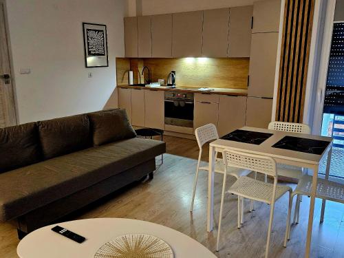 een woonkamer met een bank, een tafel en stoelen bij Apartament Studio Centrum in Człuchów