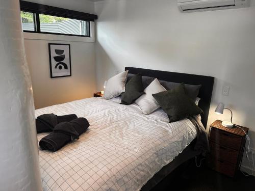 a bedroom with a bed with pillows and a window at Kauri Cabin in Gisborne