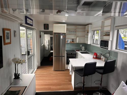 a kitchen with a refrigerator and a table with chairs at Kauri Cabin in Gisborne