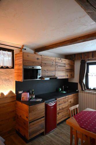 una cucina con armadi in legno e frigorifero rosso di APPARTAMENT La locanda nel bosco a Mezzana