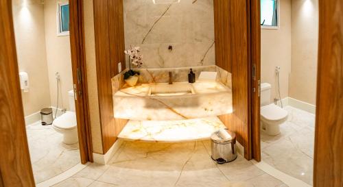 een badkamer met een marmeren bad en een toilet bij Hotel Santorini in Vila Velha