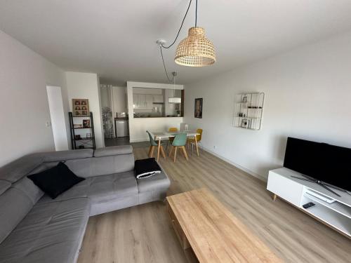 un soggiorno con un divano grigio e un tavolo di Grand T2 cosy à deux pas de Bordeaux a Cenon