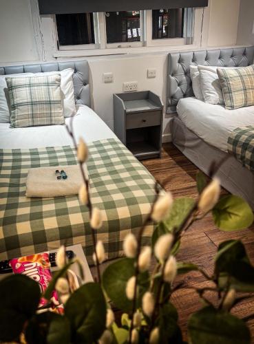 a hotel room with two beds and a table with a plant at The Kings Head in Bexley