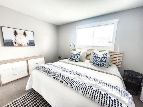 ein Schlafzimmer mit einem großen weißen Bett mit blauen Kissen in der Unterkunft Modern Lake City Getaway in Penticton