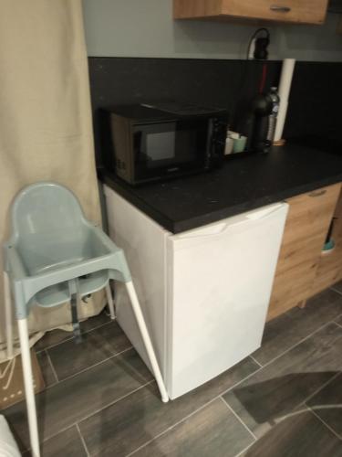 a kitchen counter with a chair and a microwave at Studio cosy in Auby