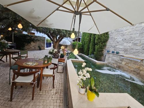 a patio with a table with an umbrella and a pond at Eleven, Boutique luxury house & garden in Boliqueime