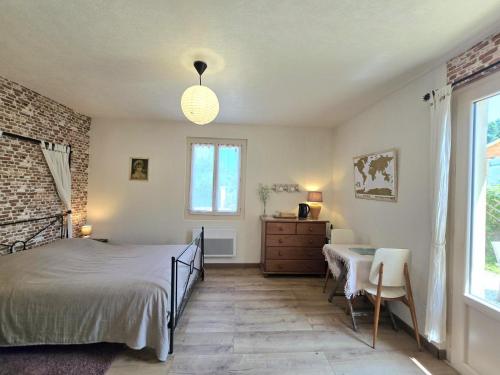a bedroom with a bed and a table and a window at Jonadam in Saint-Julien-de-Lampon