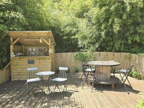 une terrasse en bois avec une table, des chaises et un bar dans l'établissement Jonadam, à Saint-Julien-de-Lampon