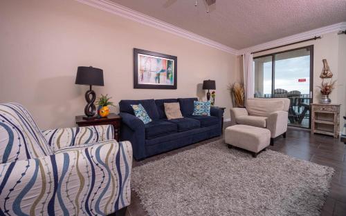 a living room with a blue couch and a chair at Phoenix East 1405 in Orange Beach