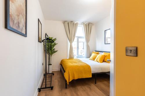 een slaapkamer met een bed met gele lakens en een raam bij Hot Tub & Sauna Retreat , 4BR with Free Parking in Portsmouth