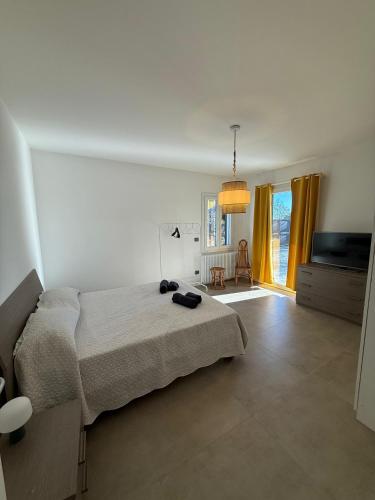 a white bedroom with a bed and a television at Villetta Brasi in Celle Ligure