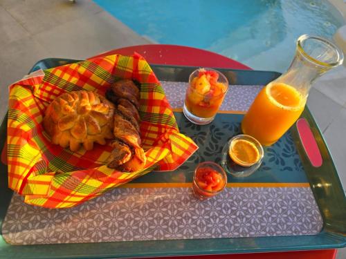 un vassoio con un piatto di cibo e un bicchiere di succo d'arancia di Eden Lodge 4 Villas avec piscine privée a Saint-François