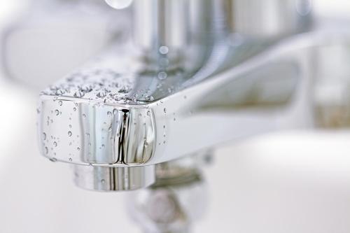 a close up of a bathroom faucet with water on it at Nordic Villa in Abuja