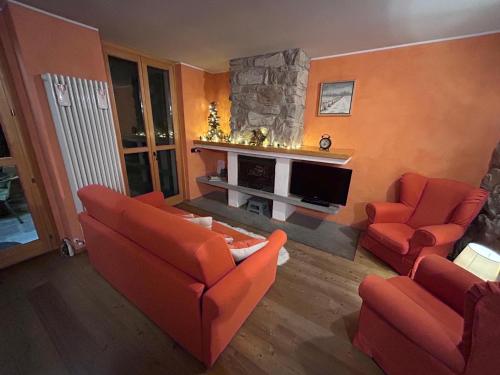 ein Wohnzimmer mit orangefarbenen Möbeln und einem Kamin in der Unterkunft Bernina House in Chiesa in Valmalenco