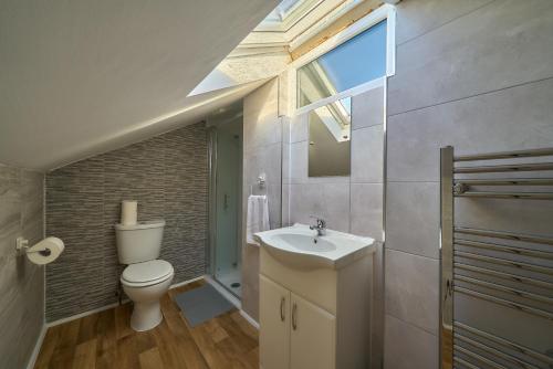 a bathroom with a toilet and a sink and a window at Chapel Road Cosy Rooms & Studios in Hounslow