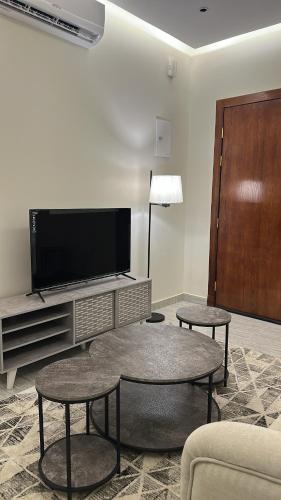 een woonkamer met 2 tafels en een flatscreen-tv bij شقه بصالة وغرفتين نوم in Hafr Al Baten