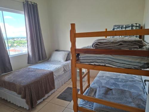 a bedroom with two bunk beds and a window at Apart próximo a Unimed, Catedral, HSA com 2 Ar e garagem in Santo Ângelo