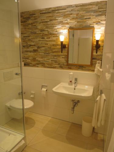 a bathroom with a sink and a toilet and a mirror at Gasthof Uthmann in Bad Iburg