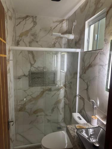 a bathroom with a shower and a toilet and a sink at Pousada Residencial A Dantas in Búzios