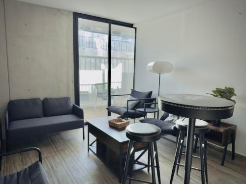 a living room with a table and stools at Depa cómodo y práctico Excelente calidad-precio Zona tranquila in Guadalajara