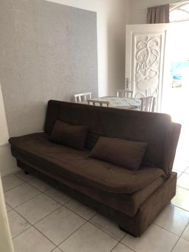 a brown couch in a living room with a table at Kitnet centro de bombinhas in Bombinhas