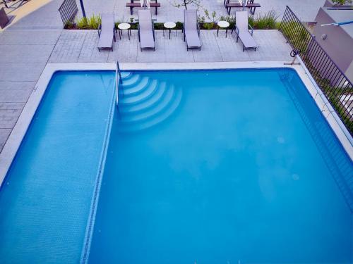 a large swimming pool with chairs and a table at Depa cómodo y práctico Excelente calidad-precio Zona tranquila in Guadalajara