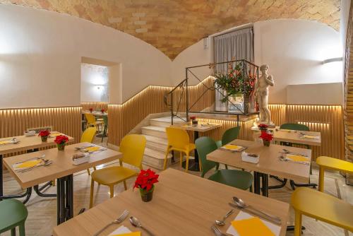 a restaurant with wooden tables and yellow chairs at Gambrinus Hotel in Rome