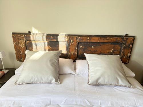 Bett mit einem Kopfteil aus Holz und weißen Kissen in der Unterkunft TRA CIELO e MARE da VALE in Fano