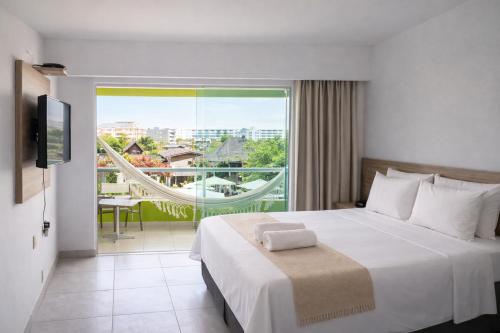 ein Hotelzimmer mit einem Bett und einem großen Fenster in der Unterkunft Pousada Solar Dos Carneiros in Praia dos Carneiros