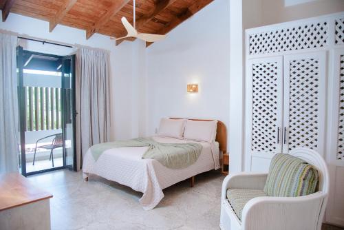 una camera da letto bianca con un letto e una sedia di Central Hotel Boutique a Las Galeras