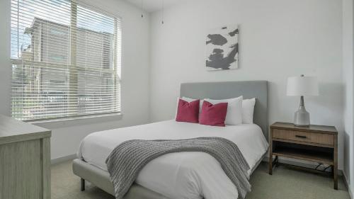 a white bedroom with a large bed with pink pillows at Landing Beautiful 2BD Pool Yoga Studio in Austin