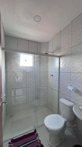 een witte badkamer met toilet en douche bij Triplex Carapibus Beach in João Pessoa