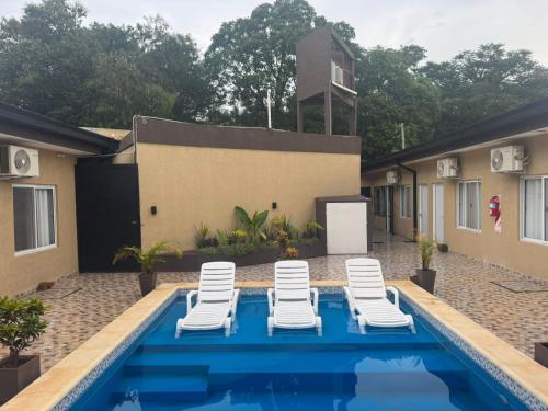a swimming pool with lounge chairs next to a house at Hotel Boutique Porá Iguazú in Puerto Iguazú